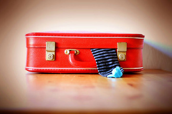 Closed red suitcase and a hanging socks