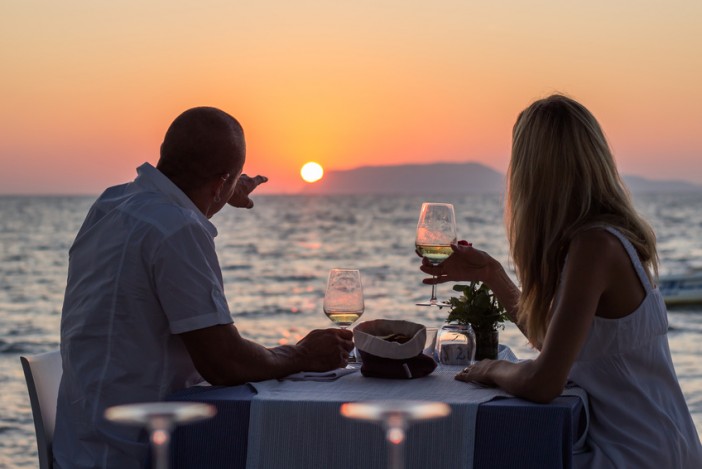 couple at dinner drinking white wine whilst enjoying the sunset on a cruise
