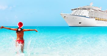 woman in santa hat splashing in the water before a cruise ship